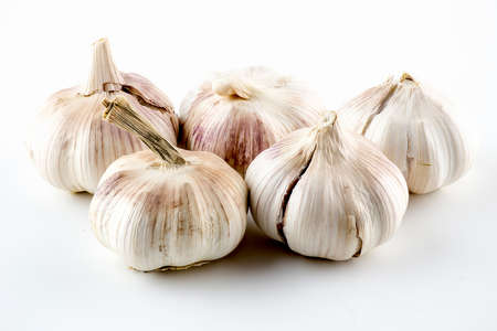 Purplish garlic heads with crackling skin isolated on whiteの写真素材