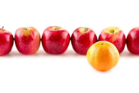 Single orange infront of line of applesの写真素材