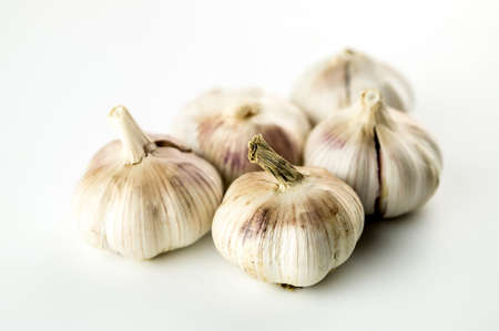 Group of unpeeled whole garlic heads isolated on whiteの写真素材