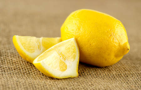 Macro of pulpy wedges of lemon next to whole fruitの写真素材