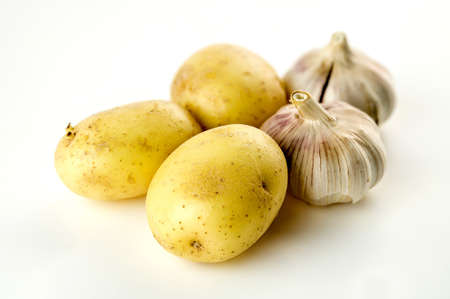 High carb unpeeled potatoes and garlic heads isolated on whiteの写真素材