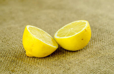 Bright yellow lemon cut in half against rustic textured hessianの写真素材