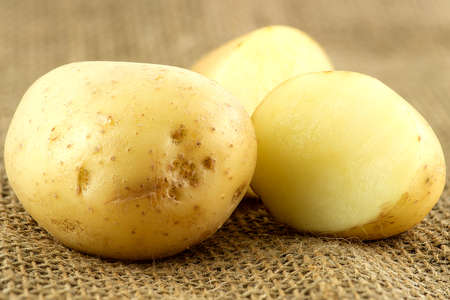 Macro of whole unpeeled potatoe next to cut piecesの写真素材