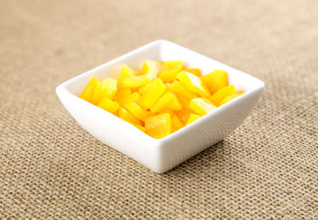 Diced yellow pepper in square container against hessian backgroundの写真素材