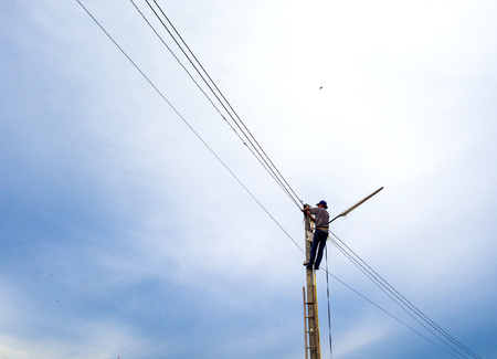 Electrician lineman repairing work on electric post power outdoor.の写真素材