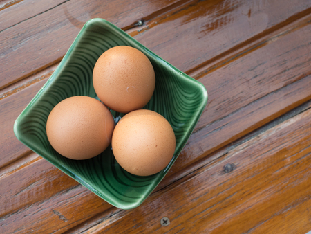 Top view of chicken eggs in a bowl on wooden background.の写真素材