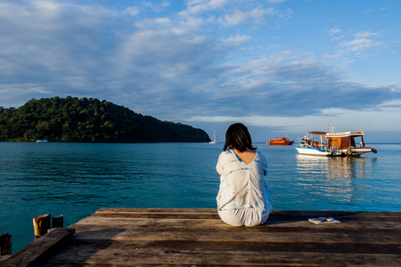 woman is relaxing on wood bridge with sunset in beautiful island, koh kood island, Trat Thailand.の写真素材
