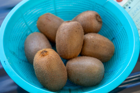 Kiwi fruit in a blue plastic basket on a blue backgroundの写真素材