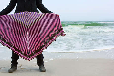 Girl in a knitted color shawl on a sea beachの写真素材