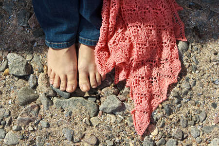 Girl with pink shawl standing on a beach stonesの写真素材