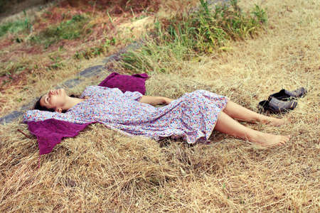 Young woman resting on a haystack after farm workの写真素材