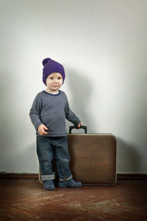 Cute boy in knitted hat with a vintage suitcaseの写真素材