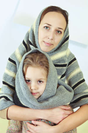 Portrait of a mother and her daughter in warm knitted shawls