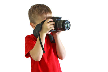 Cropped boy in a red shirt holding a camera. It stands sideways to the camera. Photographed. Studio photo on white background.の写真素材