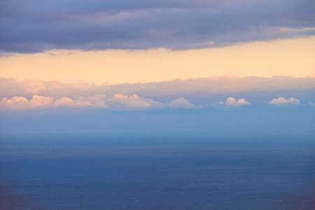 Marine horizontal landscape at sunset. The sea or ocean is clean, with no facilities. The sea becomes the sky. Horizon blurred. In her pink cloud of solar light. Beautiful sunset. Calm sea. Gloomy sky with gleams of sunshine. The sky and clouds.の写真素材