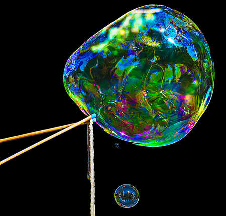 Huge bubble and a smaller one are made using two sticks and a rope.の写真素材