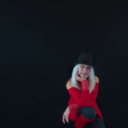 Photographer's self-portrait with copy space, wearing gray and black hat on top of white hair, red sweater and leg warmers and gray leggings.の写真素材