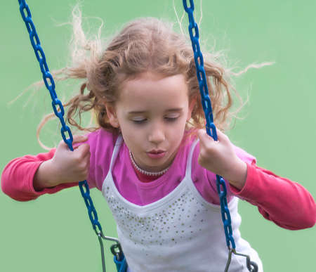 Girl dreamily swings on a swing.の写真素材