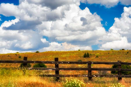 Wooden rail fence, hillside, and high desert field under cloudy sky in Tygh Valley near Redmond, Oregonの写真素材