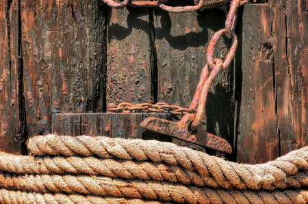 Closeup of coiled rope and rusty chain on a pier.の写真素材