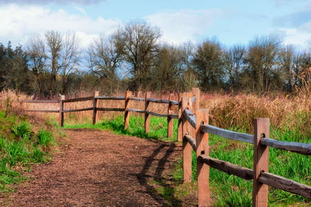 A wooden rail fence borders the path along a property line at a nature park.の写真素材