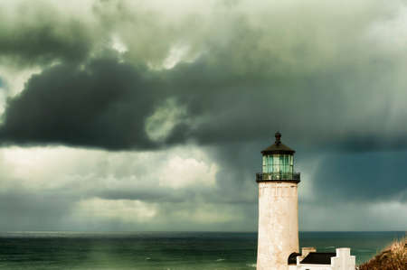Heavy clouds from stormy skies hang over the ocean while the ever present North Head Lighthouse stands in the foreground.の写真素材