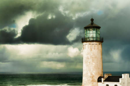 Heavy clouds from stormy skies hang over the ocean while the ever present North Head Lighthouse stands in the foreground.の写真素材