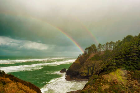 A double rainbow arches over the ocean in this scenic view from Cape Dissapointment in Washington.の写真素材