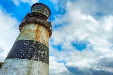 Looking up at the tower of and light of Cape Dissappointment Lighthouse against a cloudy sky.の写真素材