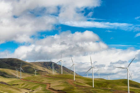 Windturbines stand tall and stark against the high desert landscape of rolling hills in the Columbia River Gorgeの写真素材
