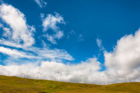 Windturbines stand tall and stark against the high desert landscape of rolling hills in the Columbia River Gorgeの写真素材
