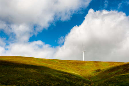 Wind Turbines stand tall and stark against the high desert landscape of rolling hills in the Columbia River Gorgeの写真素材