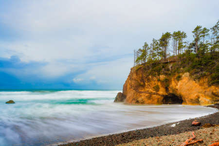 Stunning seaside landscape with sandstone cliffs topped with trees and receeding storm clouds over the horizon.の写真素材
