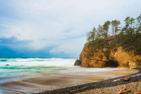 Stunning seaside landscape with sandstone cliffs topped with trees and receeding storm clouds over the horizon.の写真素材