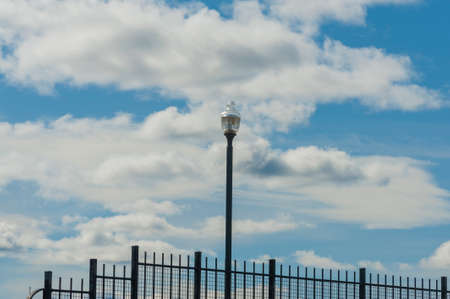 Cloudy skies a backdrop to a lone street light and iron railing.の写真素材