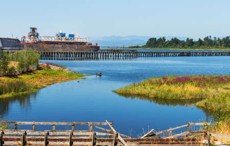 An old rusted out ship docked on the Columbia River near Astoria, Oregon, railroad tracks in the foregroundの写真素材