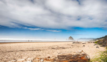 Cannon Beach, Oregon, USA - September 28.02010Blue skies emerge beneath the wind lifted clouds on Tolovana Beach, Cannon Beach, Oregon.  People strolling the shoreline in the distance.のeditorial素材