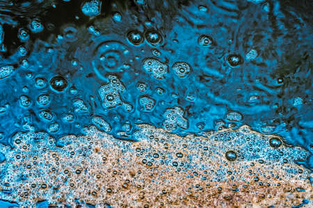 Foamy bubbles form on the top of a rain puddleの写真素材