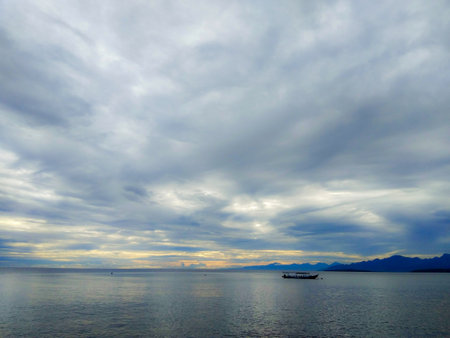 Beautiful seascape with cloudy sky and boat at sunset.