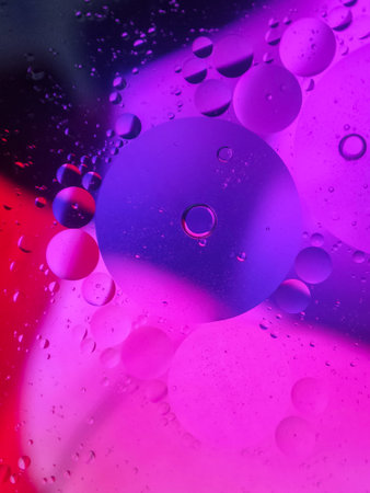 bright oily drops in water with colorful background, close-up shot