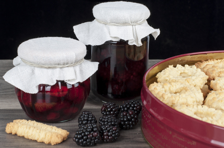 jar of homemade raspberry and blackberry confiture with fresh fruits and homemade cakesの写真素材