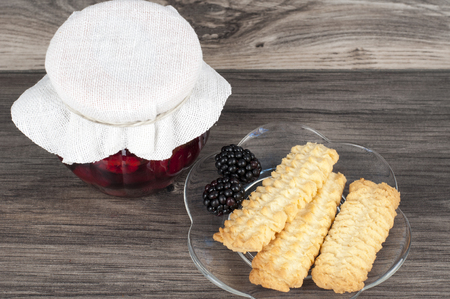 jar of homemade raspberry and blackberry confiture with fresh fruits and homemade cakes