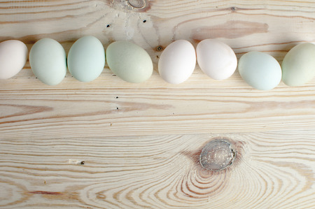 white and green eggs on wooden table; green eggs contain very little cholesterol, so they are healthierの写真素材