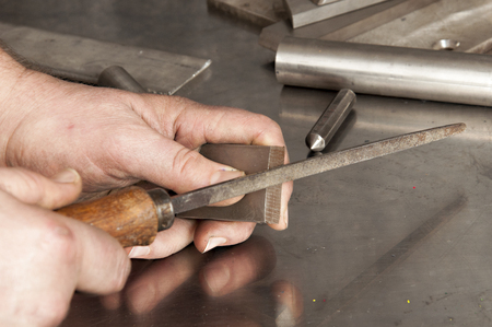 The man saws a piece of stainless steel with fileの写真素材