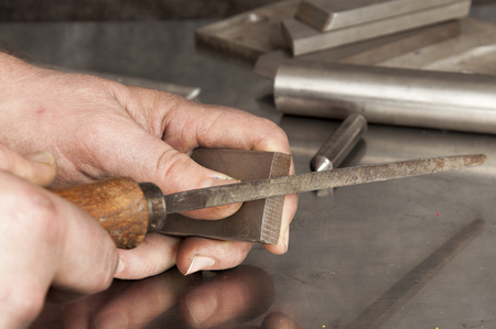 The man saws a piece of stainless steel with fileの写真素材