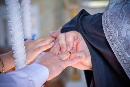 Wedding. Hands of youth with rings. Selective focus. Wedding ceremony in a Christian churchの写真素材