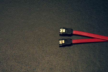 Sata computer cable on a black background. Sata as a new technology for connecting a hard drive to a computer. Satakabel communication technologyの写真素材
