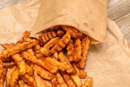Fried fries in baked goods. A parchment bag from the store with potatoes.