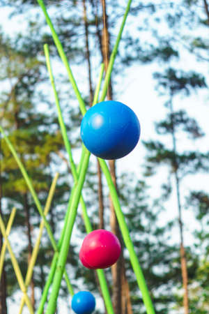 colorful hanging balls over rope wooden ladder in adventure park in forest