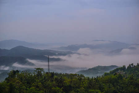 Beautiful landscape with green mountains and magnificent cloudy sky in sunrise. Buluh Payung Hill, Kebumen, Central Java, Indonesiaの写真素材